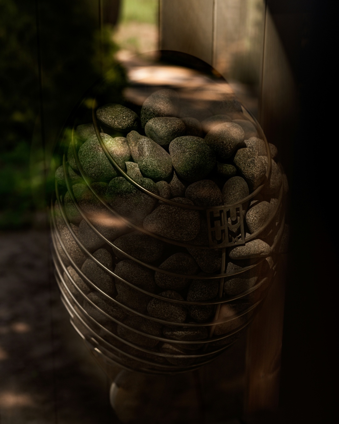Sauna heater filled with stones in dappled light