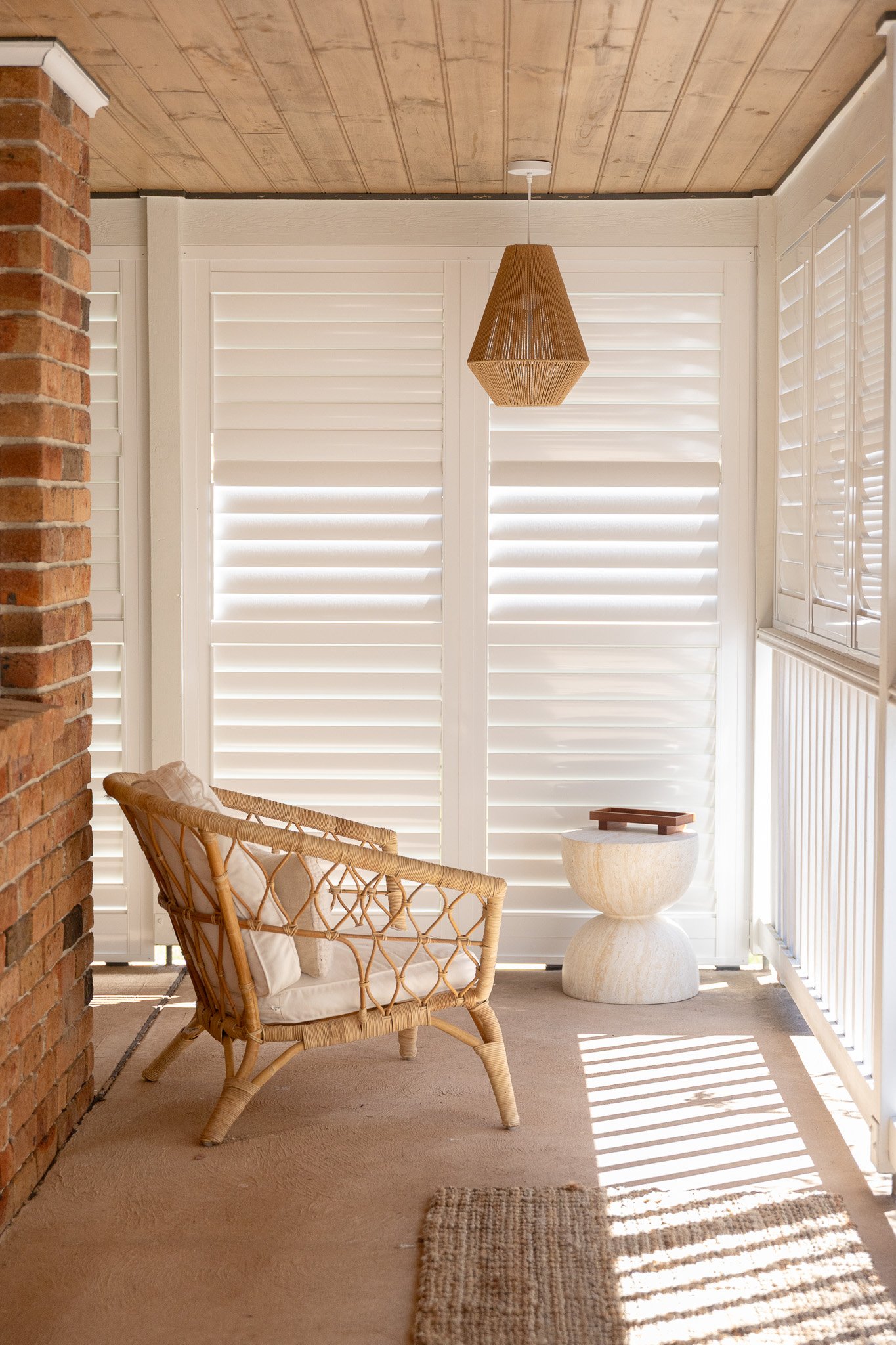 Rattan armchair and side table on a sunlit veranda